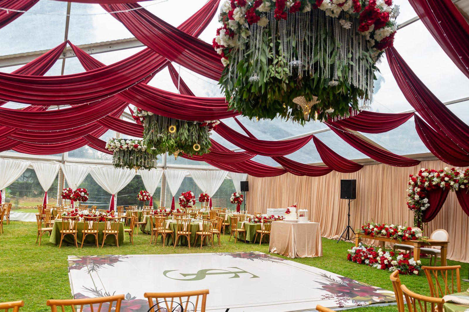 Red and ivory draping, hanging floral chandeliers and rose centrepieces in a marquee, styled by Pearls and Roses